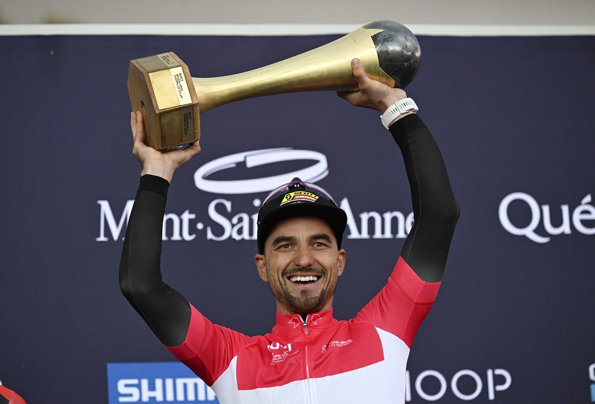 Nino Schurter, of Switzerland, raises the UCI World Cup season trophy at the men's elite class UCI mountain bike World Cup cross country cycling event in Beaupre, Quebec, Sunday, Oct. 8, 2023. (J ...