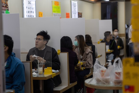 epa08347546 Patrons eat in a restaurant where tables are divided by newly installed plastic screens in Hong Kong, China, 07 April 2020. Social-distancing measures put in place by the government are li ...