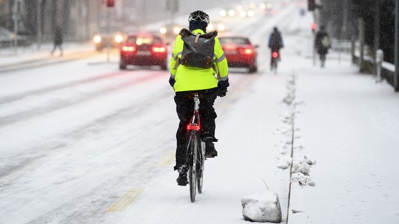 Eine Person faehrt auf dem Velo im Schnee, am Freitag, 10. Dezember 2021 in Bern. (KEYSTONE/Anthony Anex)