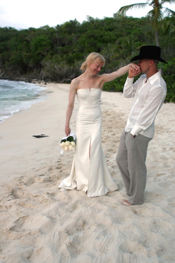 This photo from Carolina Herrera shows country music star Kenny Chesney kissing the hand of his bride, actress Renee Zellweger, wearing her Carolina Herrera designed wedding dress, on the beach in Cru ...
