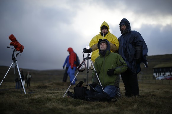 Italian visitors wait for the start of a total solar eclipse on a hill beside a hotel overlooking the sea and Torshavn, the capital city of the Faeroe Islands, Friday, March 20, 2015. For months, even ...