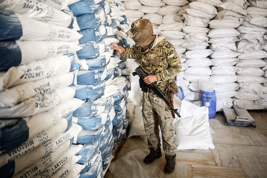epa11789246 A soldier touches bags containing a substance used to manufacture an illicit drug called captagon, which was discovered hidden inside mothballs at the warehouse where the drug was produced ...