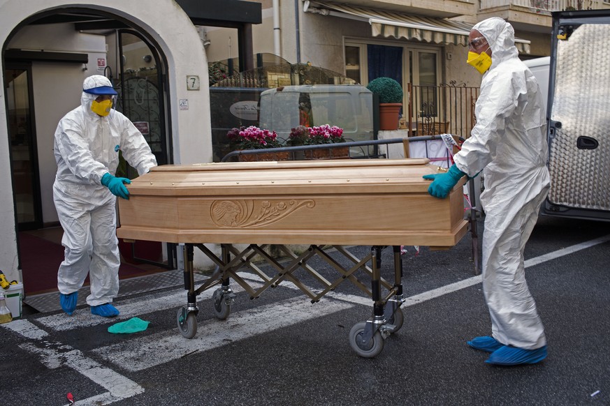 Medical staff wearing protective suits carry the coffin containing the body of Assunta Pastore, 87, after she passed away in her room at the Garden hotel in Laigueglia, northwest Italy, Liguria region ...