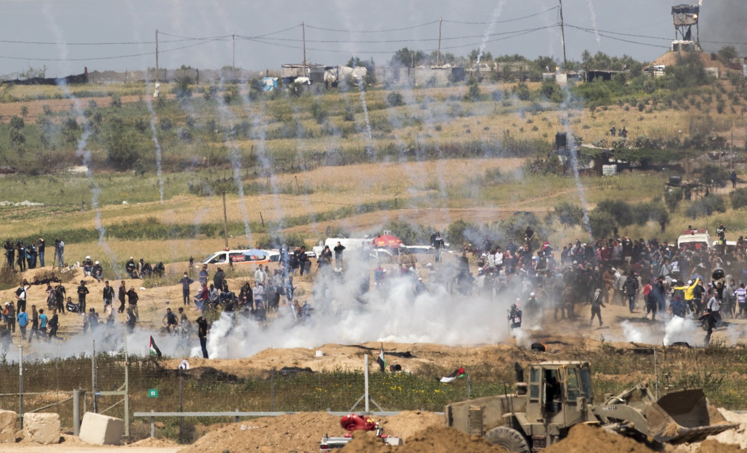 epa06649871 Tear gas canisters fired by Israeli forces fall around Palestinians from Gaza during a protest march at the Israeli Gaza border near Nahal Oz, facing the Gaza neighborhood of Shajaiyaon, 0 ...