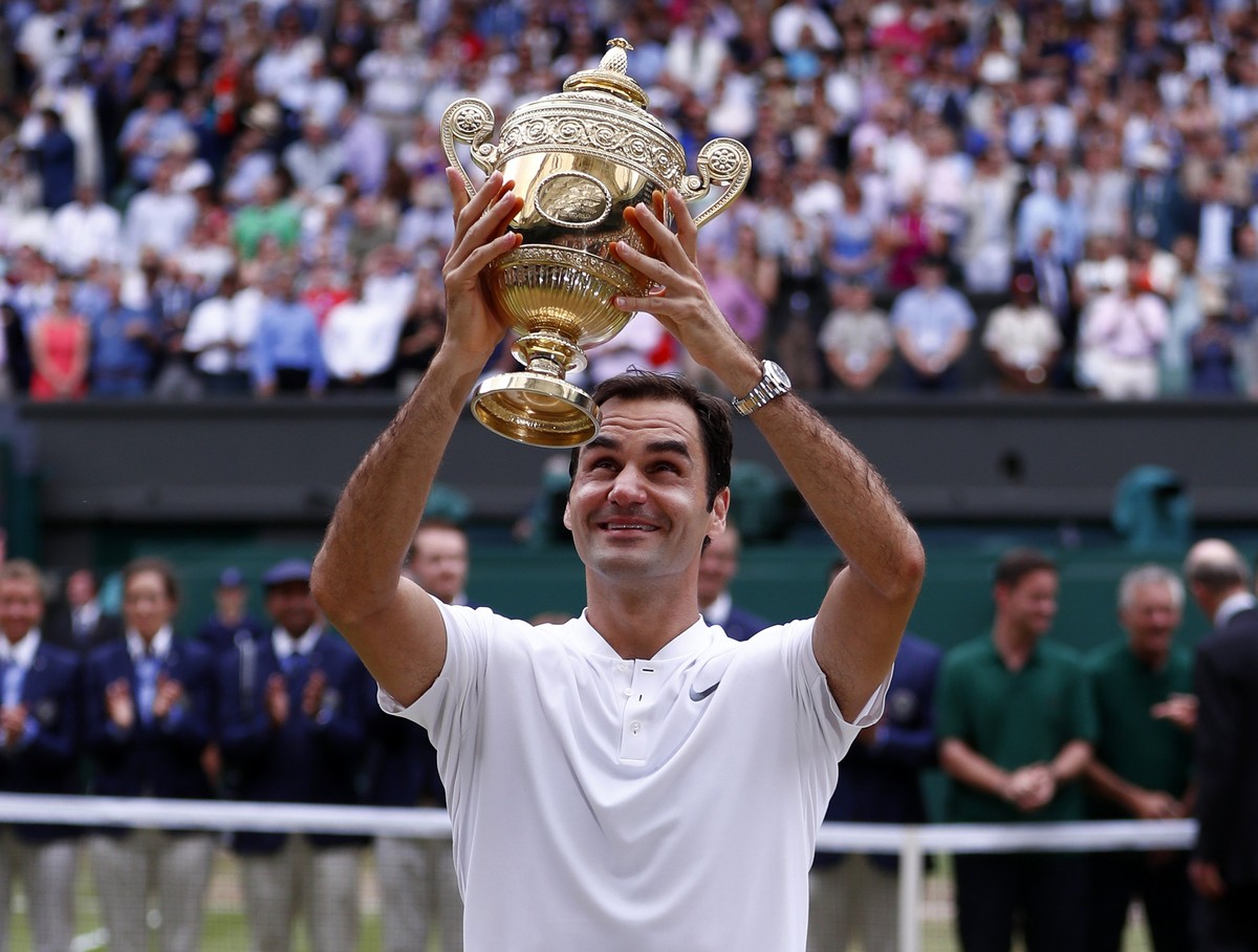 epa06091383 Roger Federer of Switzerland hoists the championship trophy following his victory over Marin Cilic of Croatia in the men's final of the Wimbledon Championships at the All England Lawn ...