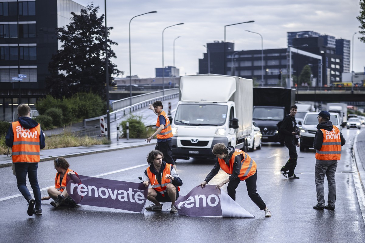 epa10699500 Environmental activists of 'Renovate Switzerland' civil resistance campaign stop vehicles as they sit down on the road during a roadblock action on the motorway A1 exit in Zueric ...