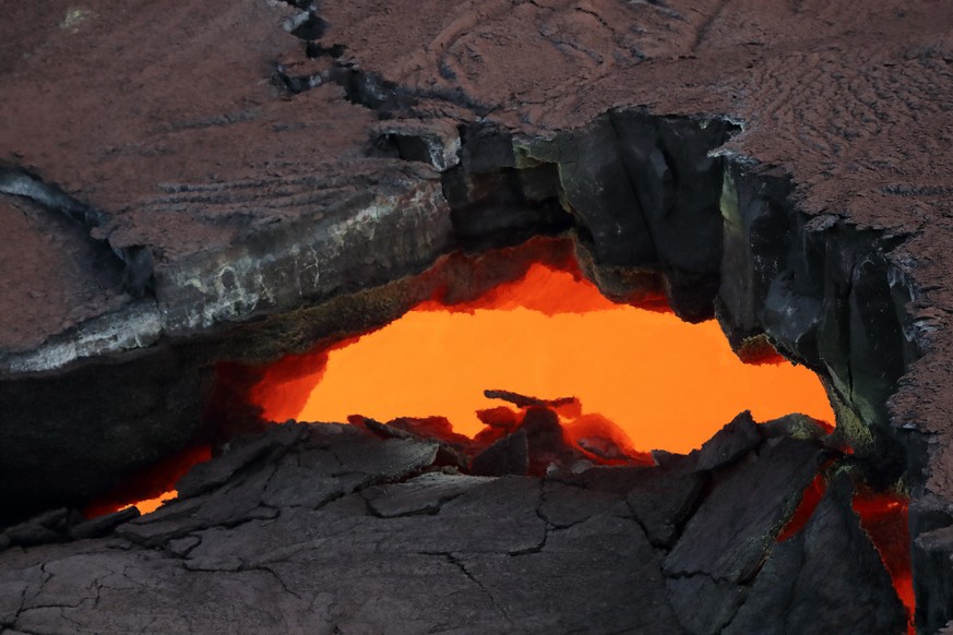 epa06708283 An view of a so-called &#039;skylight&#039;, a crack in the surface of solidified lava, taken during a Paradise Helicopters flight over the area allows a view on the hot glowing magma in a ...