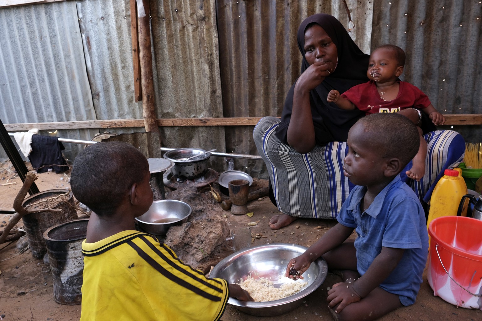 Hadiiq Abdulle Mohamed eats with her children as she speaks during an interview with Associated Press at an internally displaced people camp on the outskirts of Mogadishu, Somalia, Friday, March 24, 2 ...