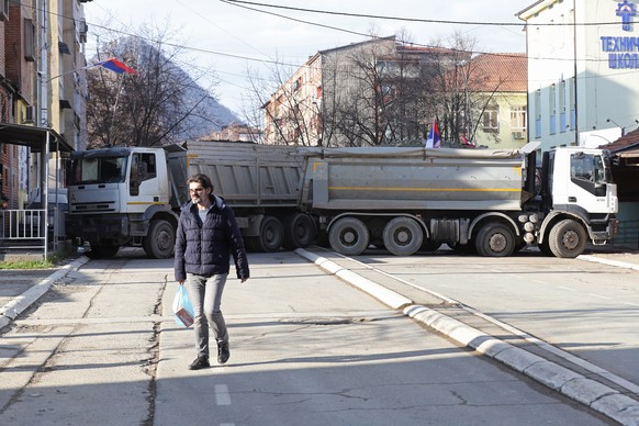 epa10381399 A resident walks past trucks blocking the road in the northern part of Mitrovica, Kosovo, December 29, 2022. Serbian President Aleksandar Vucic has stated that ethnic Serbs will begin removing…