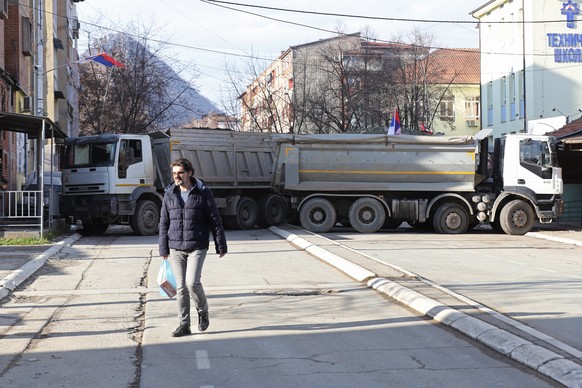 epa10381399 A resident walks past trucks blocking the road in the northern part of Mitrovica, Kosovo, 29 December 2022. Serbian President Aleksandar Vucic declared that ethnic Serbs will start removin ...