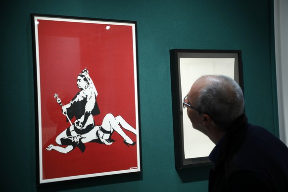 epa07116763 A man looks at posters (Queen Vic-2003) of British artist Banksy prior to a sale at the french auction house Artcurial in Paris, France, 24 October 2018. EPA/CHRISTOPHE PETIT TESSON