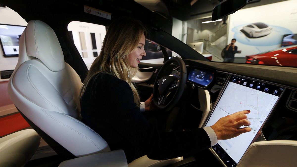 epa06213335 A woman tests a Tesla model's touchscreen display during the inauguration of US automaker Tesla's first official dealer in Spain, in L'Hospitalet de Llobregat, near Barcelon ...