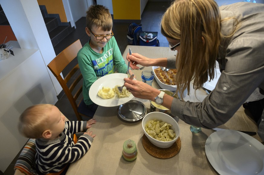 A nine-year-old boy and his 6 month old baby brother are having lunch with their mother during the school lunch break, captured in Daillens in the canton of Vaud, Switzerland, on November 5, 2014. (KE ...