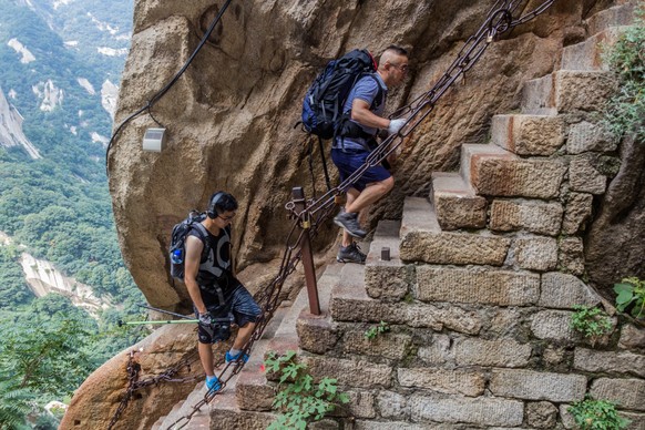 HUA SHAN, CHINA - AUGUST 4, 2018: People climb at the stairs leading to the peaks of Hua Shan mountain in Shaanxi, HUA SHAN, CHINA - AUGUST 4, 2018: People climb at the stairs leading to the peaks of  ...