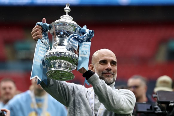 epa12964649 Manchester City's manager Pep Guardiola celebrates with the cup after winning the English FA Cup final match Chelsea FC against Manchester City, in London, Britain, 16 May 2026. EPA/N ...