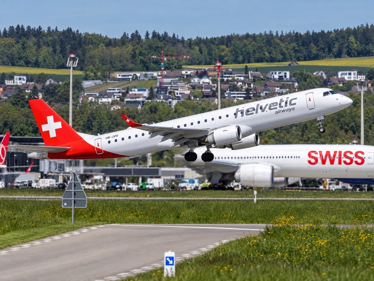 Un avion Helvetic Airways Embraer 190 à l'aéroport de Zurich en Suisse, et un appareil de la compagnie Swiss.