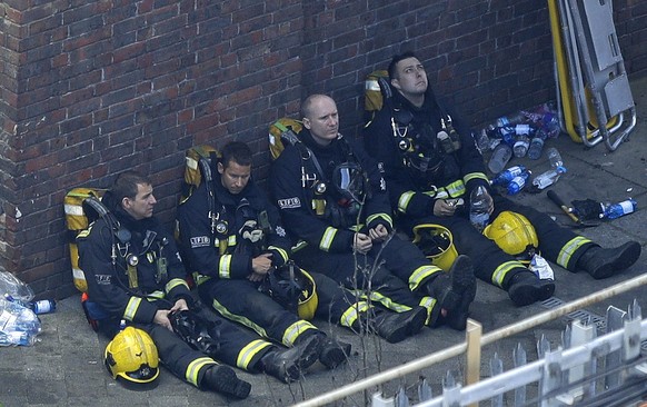 Firefighters rest as they take a break in battling a massive fire that raged in a 27-floor high-rise apartment building in London, Wednesday, June 14, 2017. Fire swept through a high-rise apartment bu ...