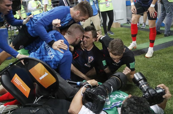 Croatia&#039;s Mario Mandzukic, sits on the ground after he fell over a photographer when celebrating his side&#039;s second goal during the semifinal match between Croatia and England at the 2018 soc ...