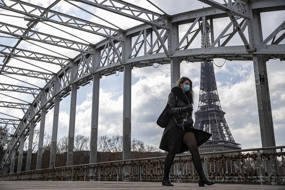 epa09083912 A pedestrian wearing a protective face mask walks across a footbridge near the Eiffel Tower  in Paris, France 19 March 2021. French Prime Minister Castex announced on 18 March additional lockdown restrictions in 16 areas of France, including Paris and the surrounding Ile-de-France region in the greater Paris region, as the country enters a third wave of the COVID-19 pandemic. The new lockdown restrictions , which go into effect at midnight on Friday 19 March, include the closure of 'non-essential' businesses (although schools remain open), a form is required to be outdoors within a 10 kilometer radius of one's home, and a curfew from 7pm to 6am remains in place.  In the hours counting down to the  application of the new restrictions, Parisians queued outside clothing retail shops and home furniture stores, anticipating their closure for a minimum of 4 weeks.  EPA/IAN LANGSDON