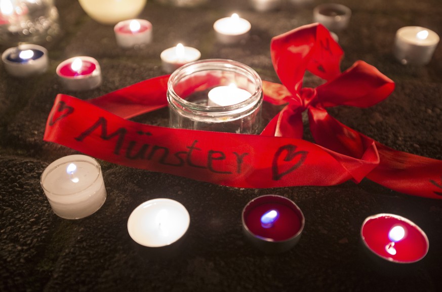 In this Saturday, April 7, 2018 photo a ribbon with the writing &#039;Muenster&#039; sits between candles in Muenster, western Germany where a van crashed into people drinking outside a popular bar vo ...