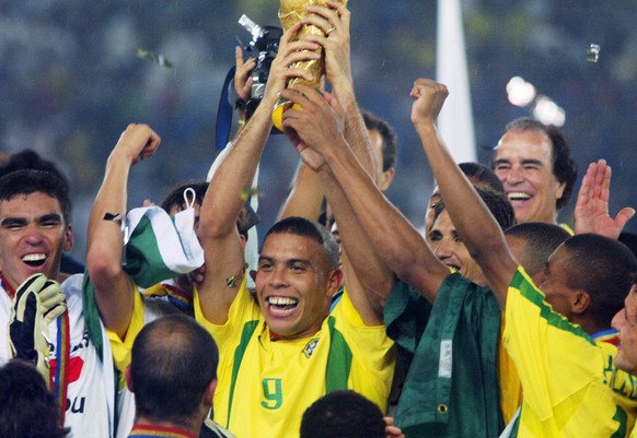 EH110 - 20020630 - YOKOHAMA, JAPAN : Brazil&#039;s forward Ronaldo (C), flanked by teammates, hoists the World Cup trophy as confetti fall over the pitch during the award ceremony at the International ...