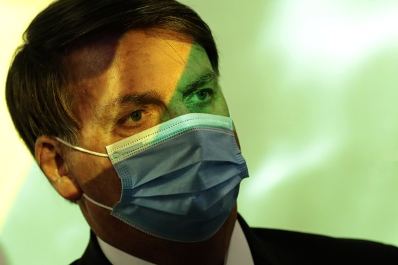 President Jair Bolsonaro wears a mask amid the COVID-19 pandemic at the start of a ceremony where the national flag is projected in Brasilia, Brazil, Wednesday, Aug. 5, 2020. (AP Photo/Eraldo Peres)
J ...