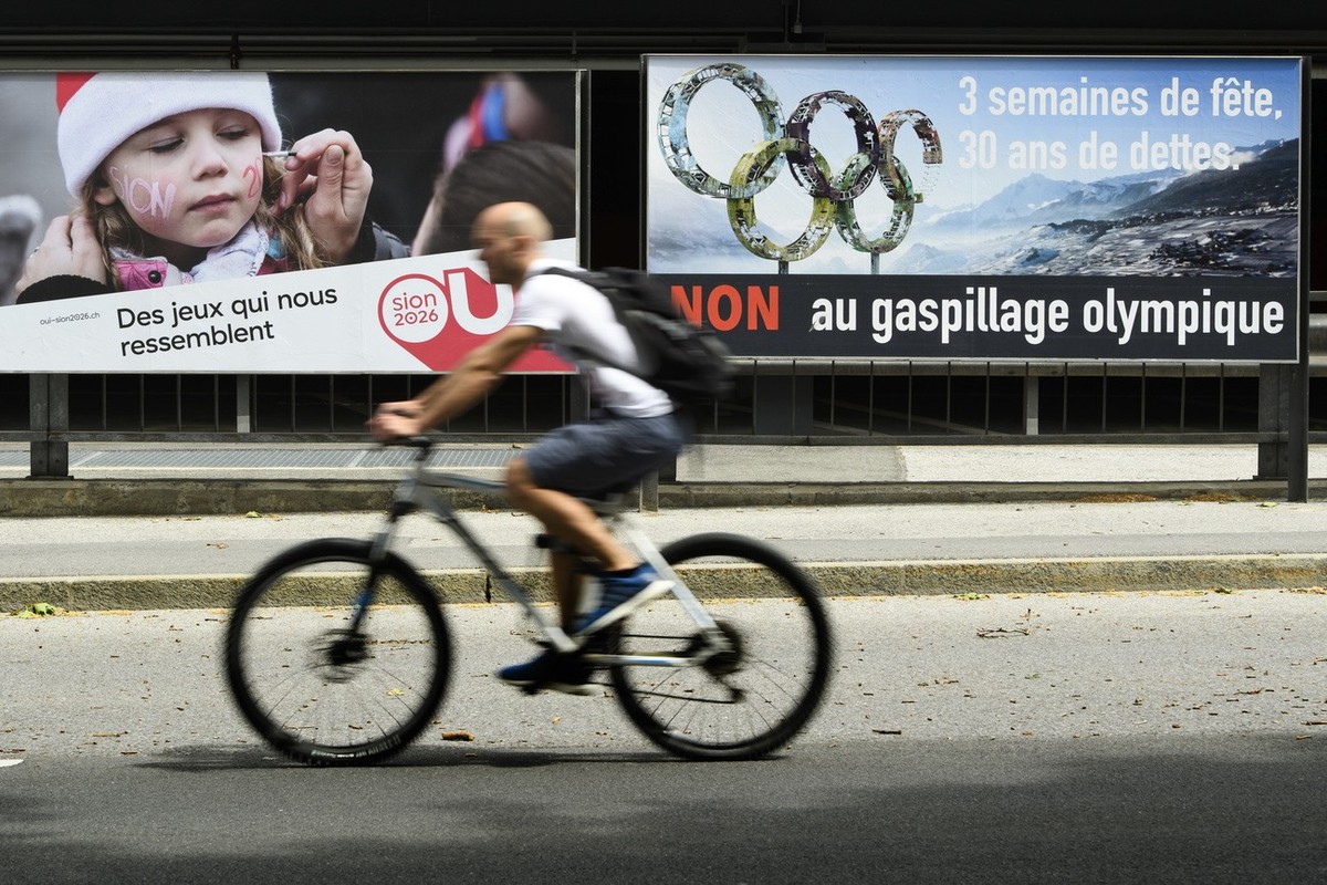 Un cycliste roule proche d'une affiche des partisants, gauche, et des opposants, droite, au projet Sion 2026 ce dimanche 27 mai 2018 a Sion. La population valaisanne doit dire le 10 juin prochain ...