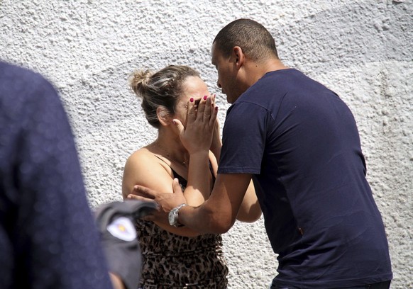 A man comforts a woman at the Raul Brasil State School in Suzano, Brazil, Wednesday, March 13, 2019. The state government of Sao Paulo said two teenagers, armed with guns and wearing hoods, entered th ...