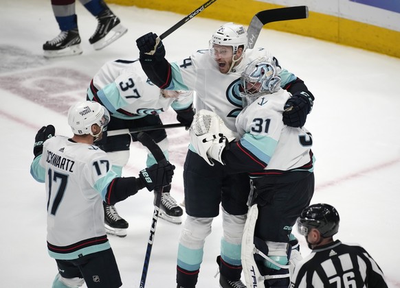 From left, Seattle Kraken center Jaden Schwartz, defenseman Jamie Oleksiak and goaltender Philipp Grubauer celebrate as time runs out in the third period of Game 7 of an NHL first-round playoff series ...