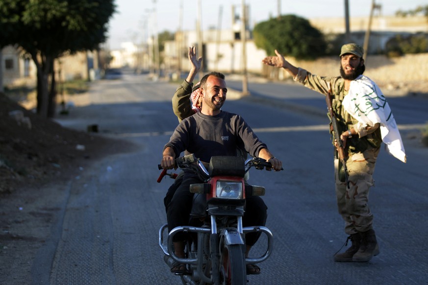 REFILE - CORRECTING STYLE OF TOWN NAMEResidents driving a motorcycle gesture towards a fighter in Dabiq town, northern Aleppo countryside, Syria October 16, 2016. REUTERS/Khalil Ashawi