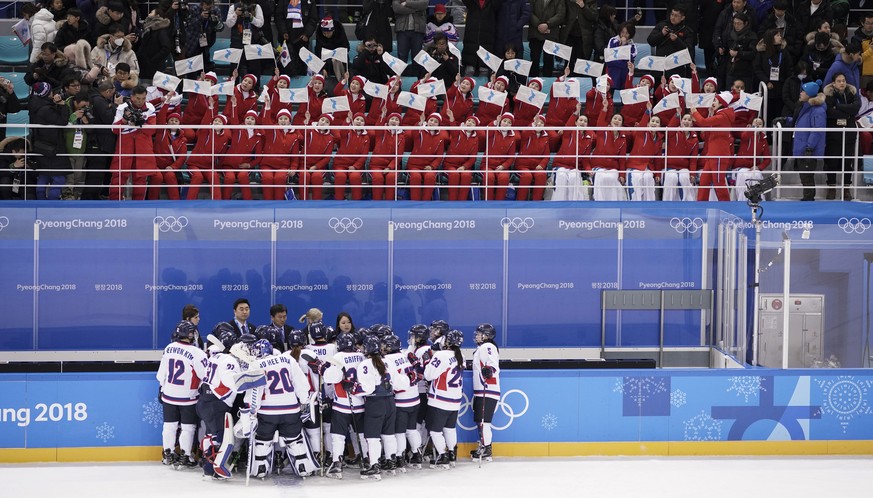 North Korea supporters, top, wave the Korean unification flag as players of combined Koreas gather at the end of a women&#039;s hockey game against Switzerland at the 2018 Winter Olympics in Gangneung ...