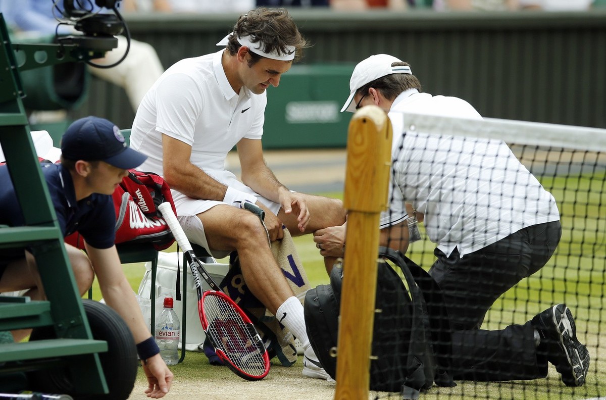 FILE - In this July 8, 2016, file photo, Roger Federer of Switzerland receives medical attention during his men's semifinal singles match against Milos Raonic of Canada at the Wimbledon Tennis Ch ...