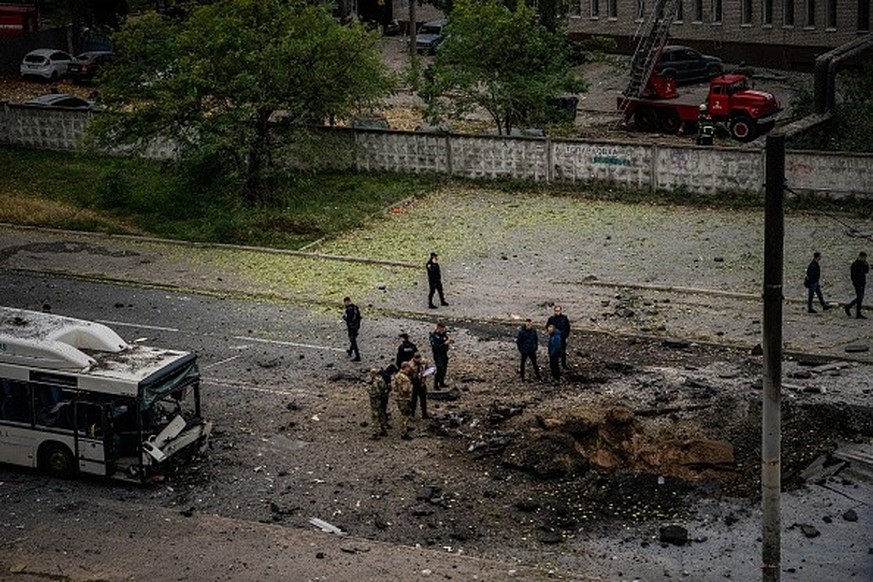 TOPSHOT - Investigators examine a crater next to a damaged bus, following a missile strike in Dnipro on October 10, 2022, amid Russia&#039;s invasion of Ukraine. - The head of the Ukrainian military s ...