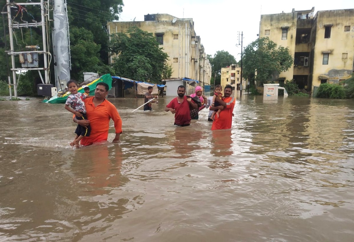 epa07753207 A handout photo made available by the India's National Disaster Response Force (NDRF) shows NDRF team busy in the rescue operation in the flooded street of Vadodara area in Gujarat, I ...