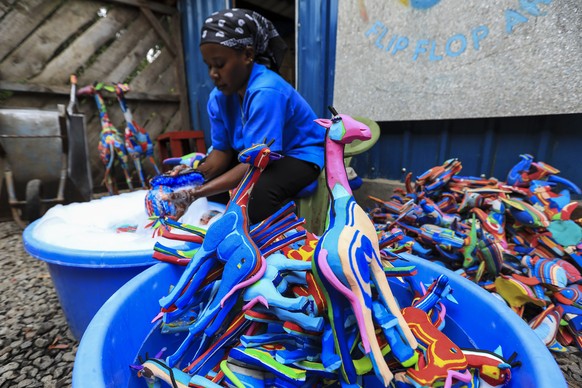 epa10228972 A Kenyan worker from the social enterprise &#039;Ocean sole&#039; cleans art pieces made from recylcled flip-flops before drying them at their workshop in Nairobi, Kenya, 06 October 2022 ( ...