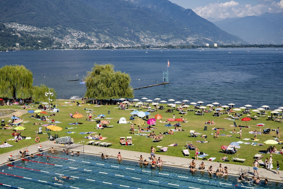 Des personnes profitent de le piscine du Lido au bord du lac Majeur lors d'une chaude journee d'ete le samedi 10 aout 2024 a Locarno. La vague de chaleur au Sud des Alpes se renforce netteme ...