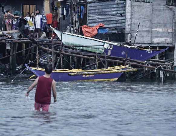 epa12404690 A fisherman approaches fishing boats placed on high ground in anticipation of an approaching typhoon in Cavite City, Philippines, 25 September 2025. The Philippine weather bureau advised t ...