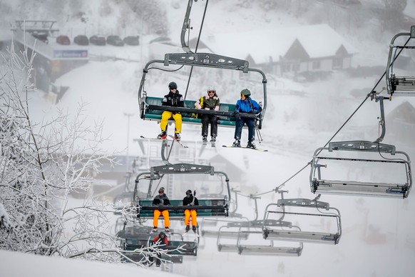 01.12.2023, Nordrhein-Westfalen, Winterberg: Freizeitsportler sitzen in einem Sessellift. In den Ski-Gebieten rund um Winterberg beginnt die Wintersportsaison. Den Er