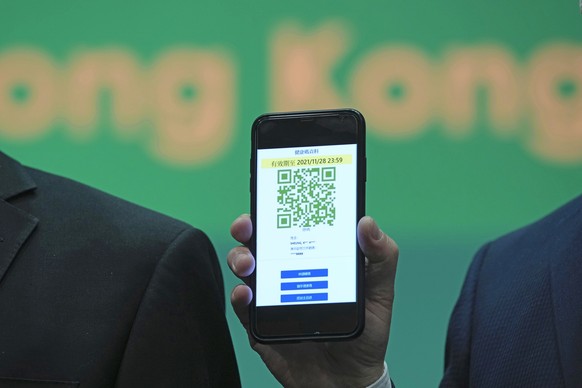 Secretary for Innovation and Technology Alfred Sit holds a mobile phone to unveil a new COVID-19 tracking health code mobile app during a news conference in Hong Kong, Thursday, Dec. 2, 2021. The mobi ...