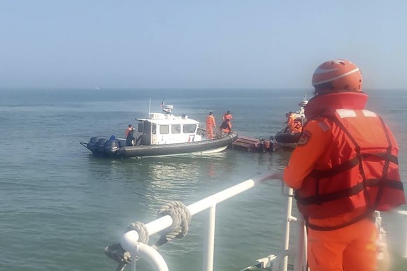 In this photo provided by the Taiwan Coast Guard Administration, Taiwanese coast guards inspect a ship that capsized during a chase off the coast of Taiwan's Kinmen Archipelago, Wednesday...
