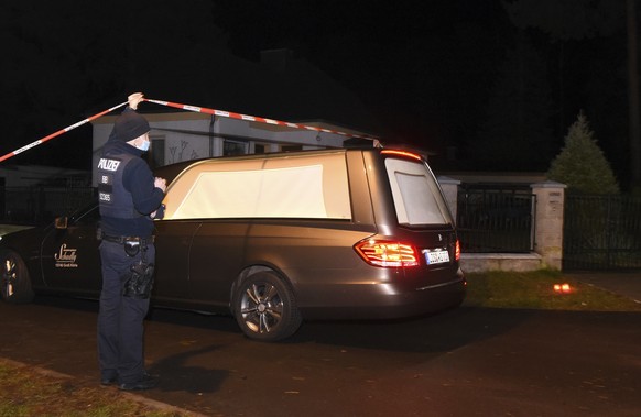 A hearse drives to an apartment building in Koenigs Wusterhausen, Germany, Saturday, Dec. 4, 2021. Five bodies with gunshot and stabbing wounds were found Saturday in a house just outside Berlin, Germ ...