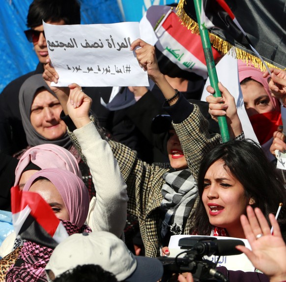 epa08215346 An Iraqi woman carries a plascard reading in Arabic &#039;Women are half of society&#039; during a protest at the Al-Tahrir square in central Baghdad, Iraq, 13 February 2020. Hundreds of I ...