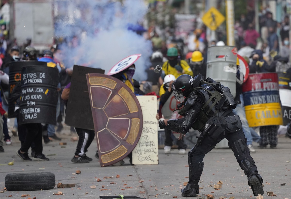 A police officer throws a stun grenade at protesters during an anti-government protest triggered by proposed tax increases on public services, fuel, wages and pensions in Bogota, Colombia, Monday, Jun ...