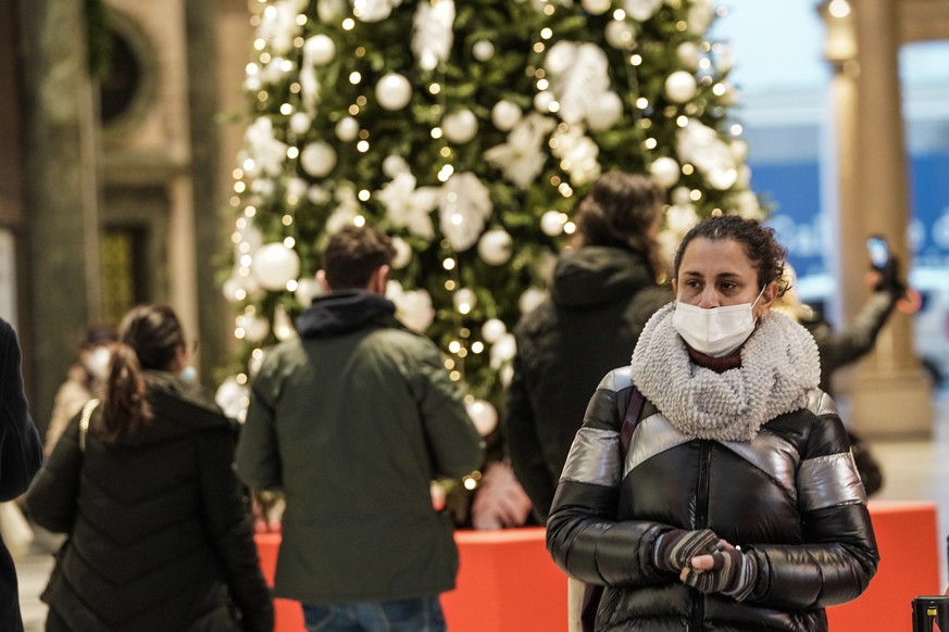 epa09619378 A woman wears a mask as she walks past a Christmas tree in Turin, Italy, 03 December 2021. EPA/TINO ROMANO