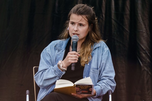 epa09377364 German climate activist Luisa Neubauer reads during a presentation of their book ?Noch haben wir die Wahl? (We still have the Choice) in Berlin, Germany, 29 July 2021. The book ?Noch haben ...