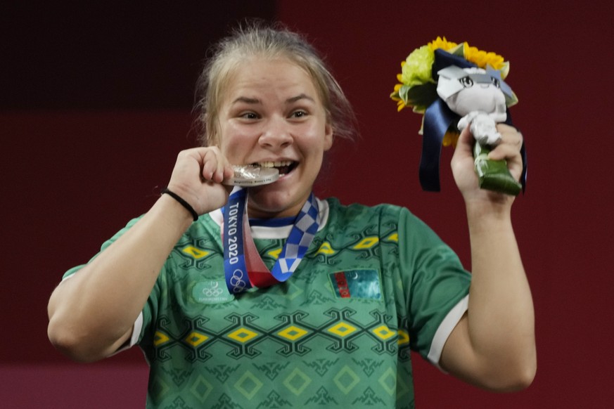 Polina Guryeva of Turkmekistan celebrates on the podium after winning the silver medal in the women&#039;s 59kg weightlifting event, at the 2020 Summer Olympics, Tuesday, July 27, 2021, in Tokyo, Japa ...