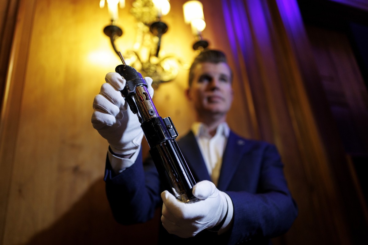epa12285905 A staff member poses with a film prop used as Darth Vader's dueling lightsaber in the 'Star Wars: Episode V - The Empire Strikes Back' and 'Star Wars: Episode VI - Retu ...