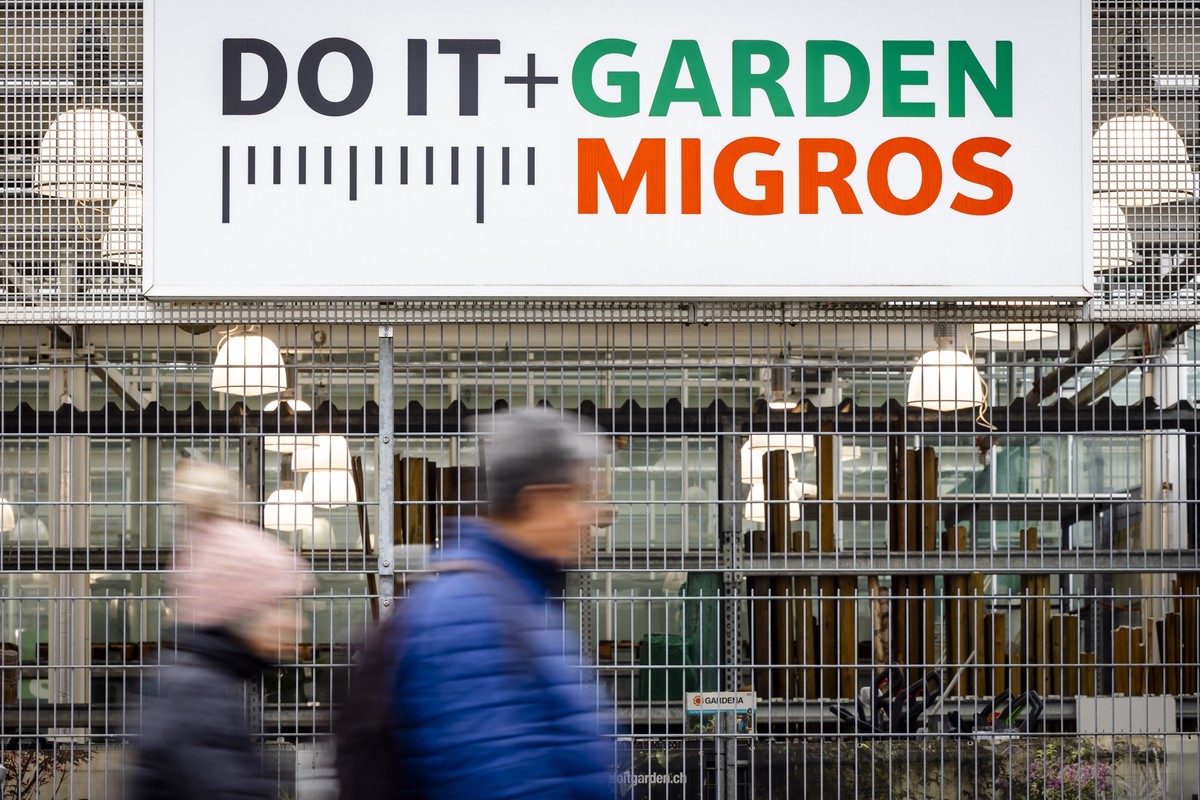 Zwei Personen gehen an einem Logo einer Do it + Garden Filiale vorbei, aufgenommen am Dienstag, 25. Februar 2025 in Buelach. Die Migros setzt ihre Konzentration aufs Kerngeschaeft fort. Der Detailhaen ...