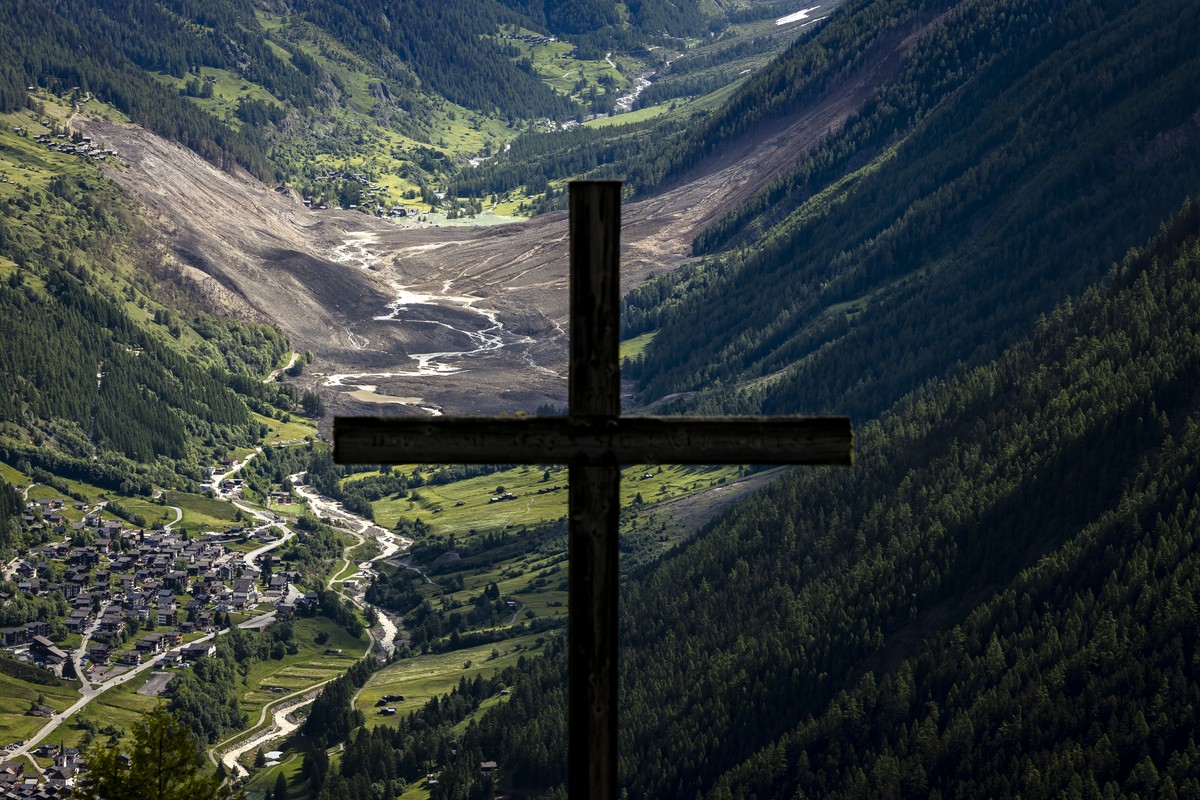 epa12160285 A wooden Christian cross is silhouetted against a massive avalanche triggered by the collapse of the Birch Glacier, which swept down to the valley floor and destroyed the village of Blatte ...