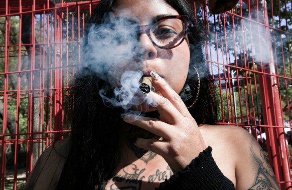 epa09064563 A woman smokes during a march for the full regularization of cannabis, in Mexico City, Mexico, 09 March 2021. Activists and cannabis consumers marched as the full chamber of the Lower Hous ...